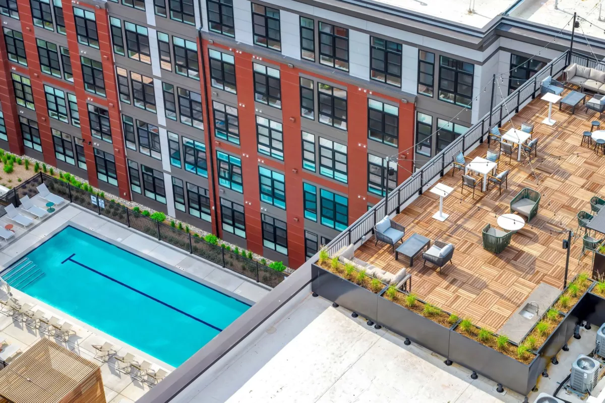 Rooftop terrace with seating, string lights, and view of pool below.