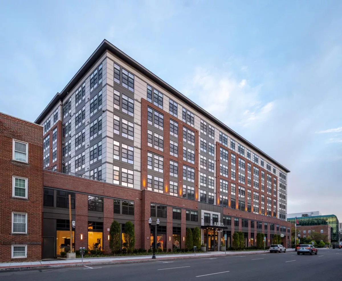 Exterior of an apartment building with a mix of red and gray facade with abundant windows.