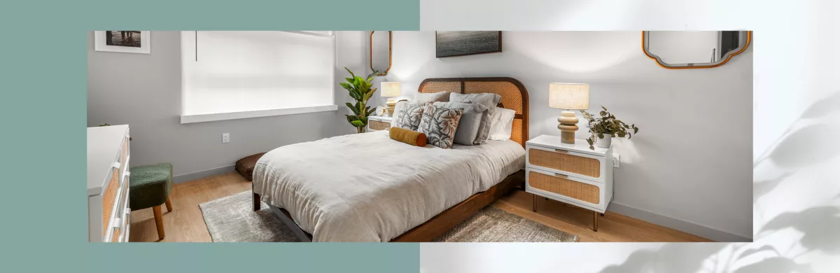 Bedroom with white walls, wood-style flooring, stylish art and mirrors, and window shades that rise from the bottom.